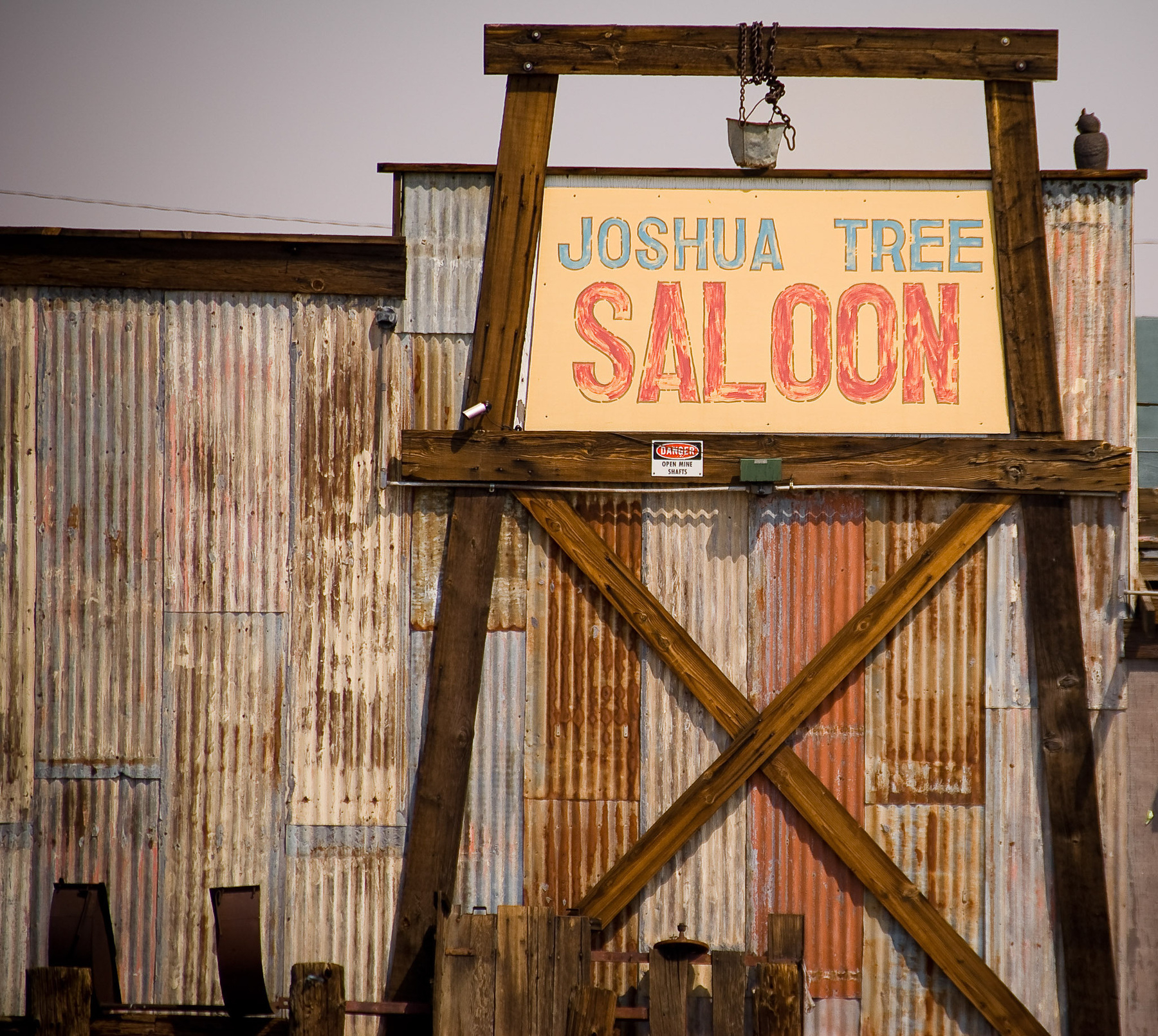 A rustic wooden sign reading Joshua Tree Saloon is displayed in front of a weathered corrugated metal building.