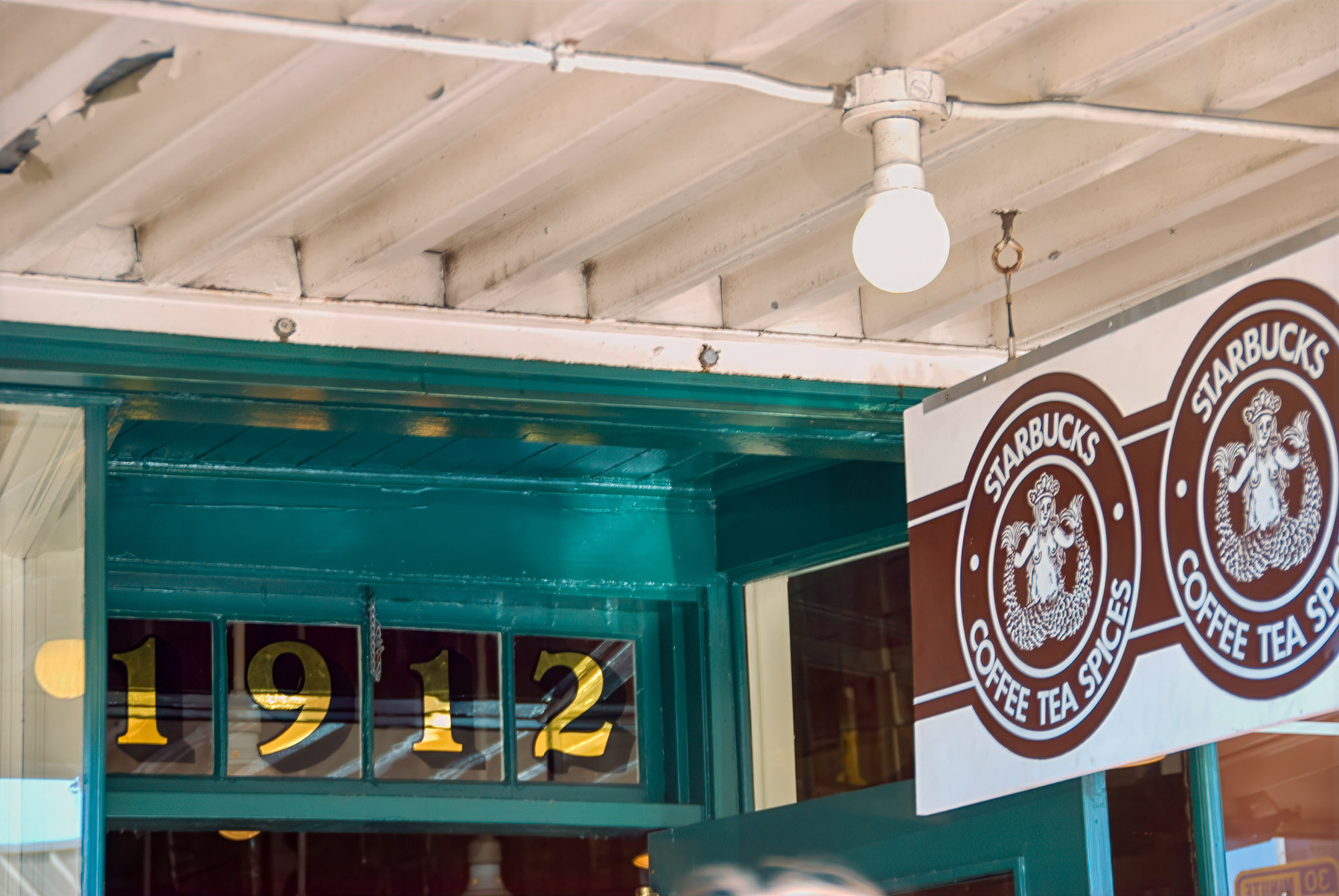 A store with a sign displaying 1912 above a Starbucks coffee, tea, and spices logo.