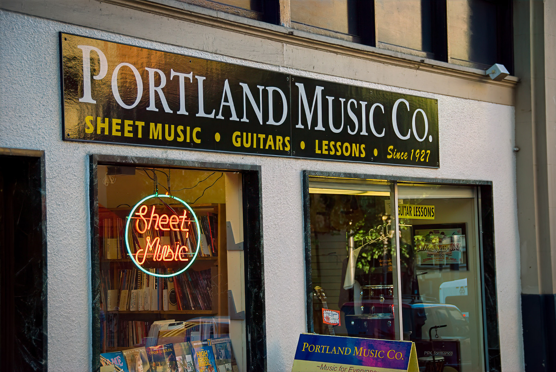 Portland Music Co. is a store offering sheet music, guitars, and music lessons, with a neon Sheet Music sign in the window.