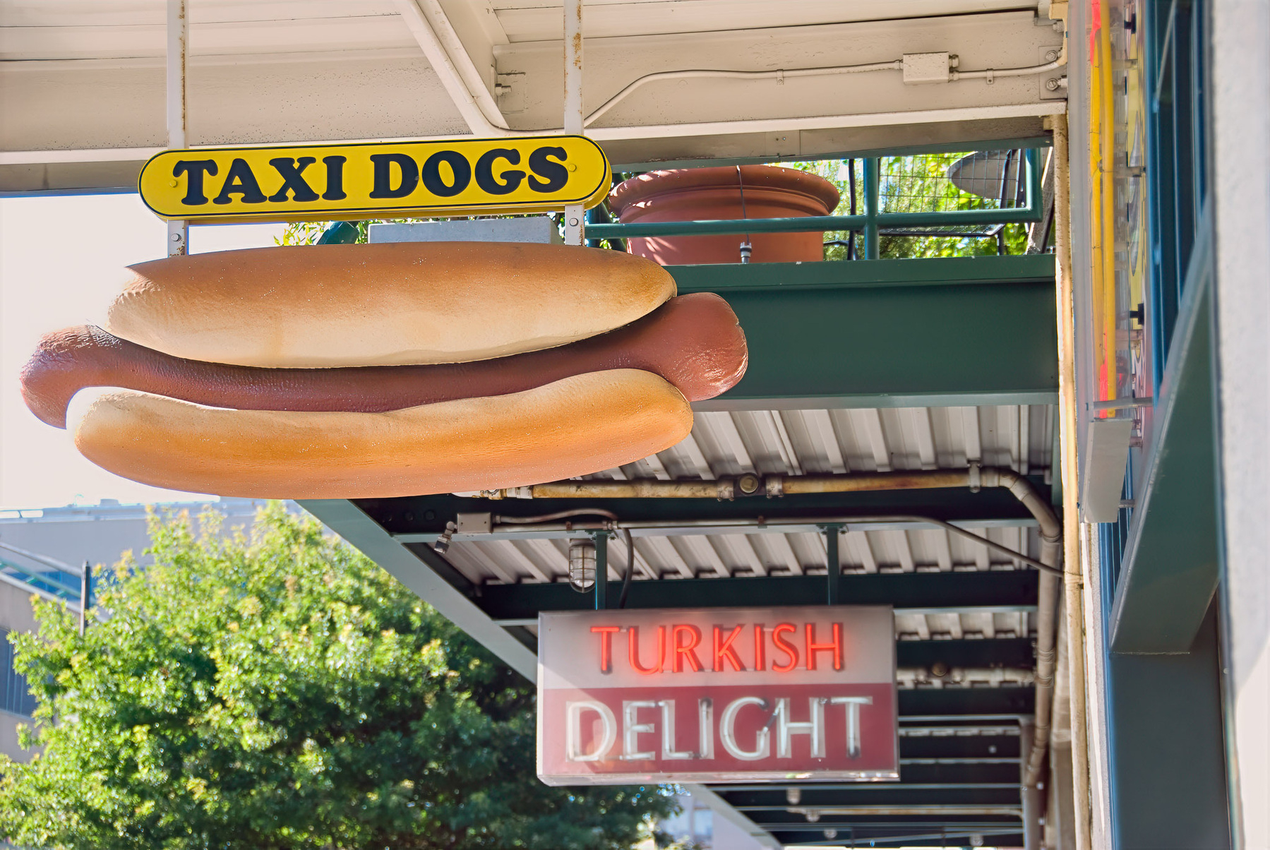 A hot dog shop sign and a Turkish Delight sign hang under an outdoor walkway.