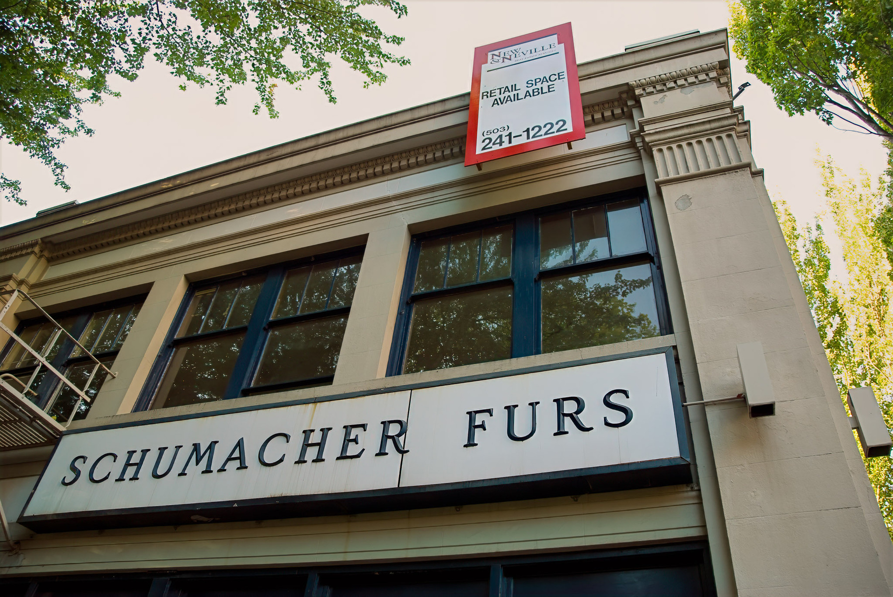 A building facade features a sign for SCHUMACHER FURS and another sign indicating retail space available.