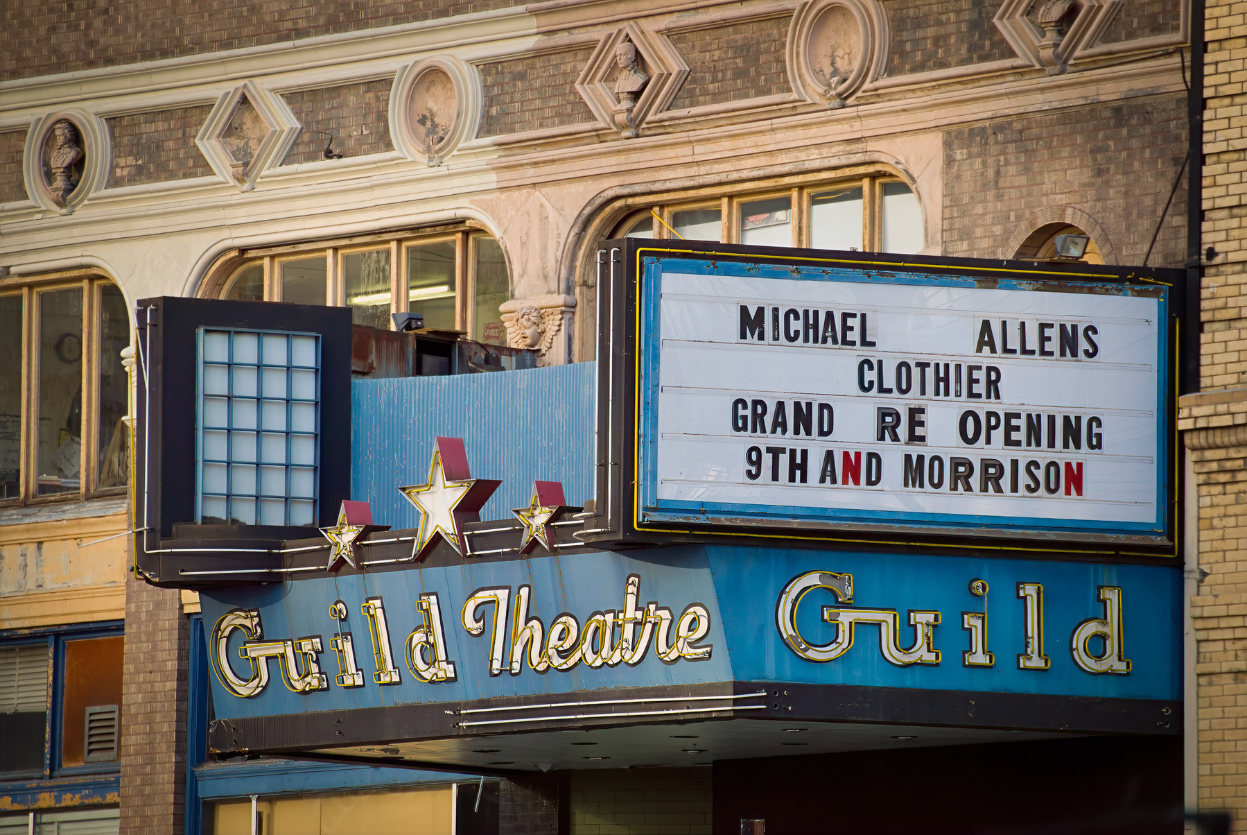 A vintage theater marquee advertises a Grand Reopening for Michael Allens Clothier at 9th and Morrison.