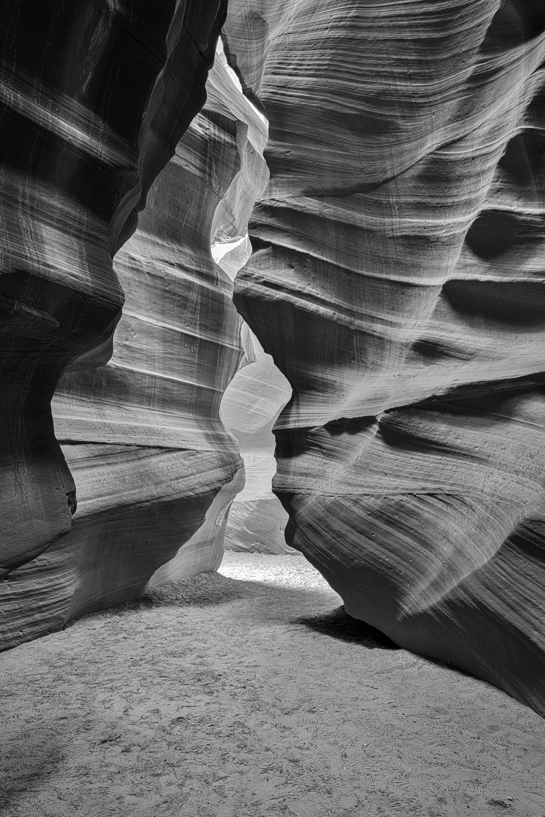 Auto-generated description: A narrow, textured sandstone canyon with flowing lines has a naturally carved pathway leading through it.